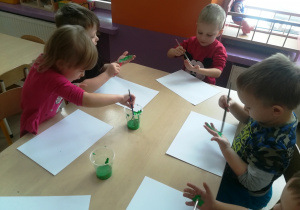 Dzieci malują dłonie zieloną farbą